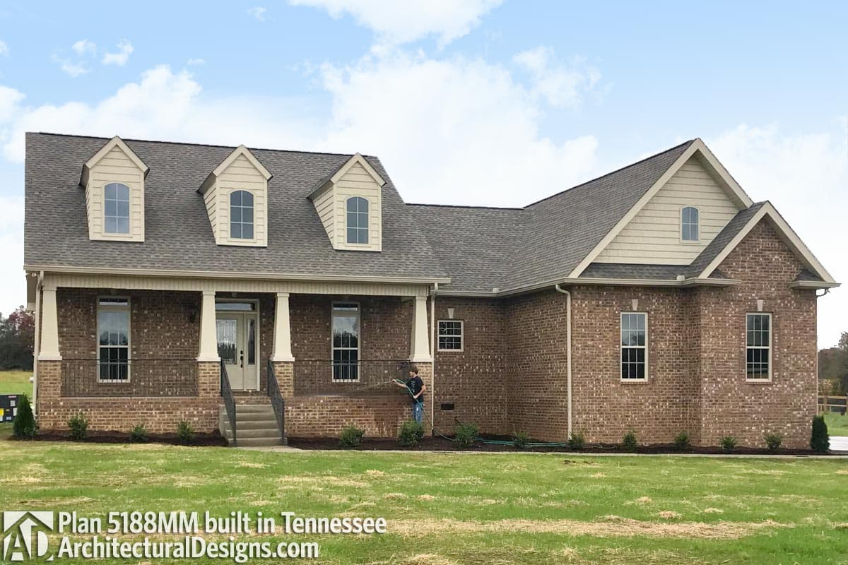 House plan exterior: Brick ranch with covered front porch, dormers, and multi-gabled rooflines.