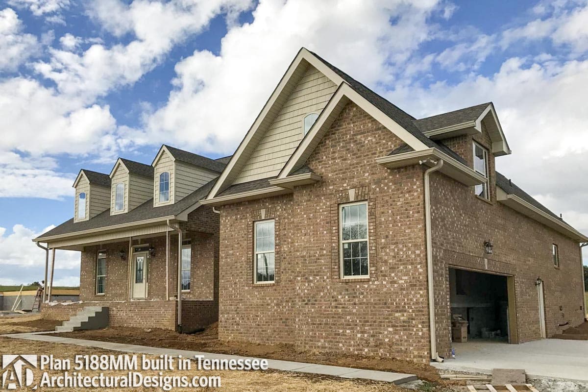 House plan exterior featuring brick facade, front porch, gable dormers, and side-entry garage.