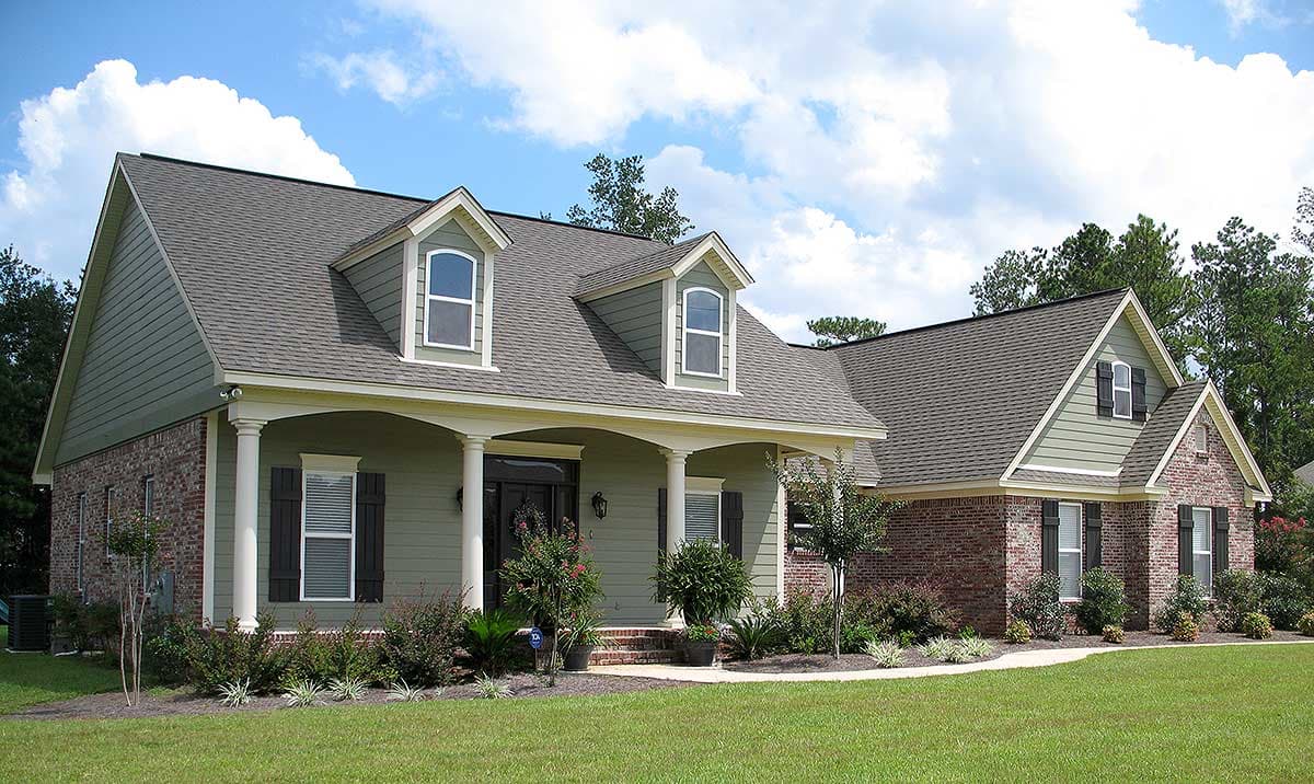House plan exterior: Traditional style with a covered front porch, brick accents, dual dormers, and a multi-gable roof.