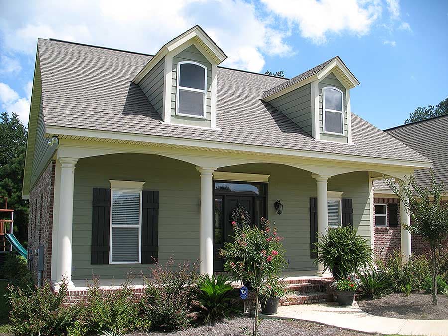 House plan exterior of a one-story home with arched front porch, dormers, and brick and siding accents.