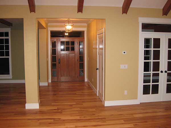 Interior view of entryway with wood door, adjacent French doors, and exposed ceiling beams.