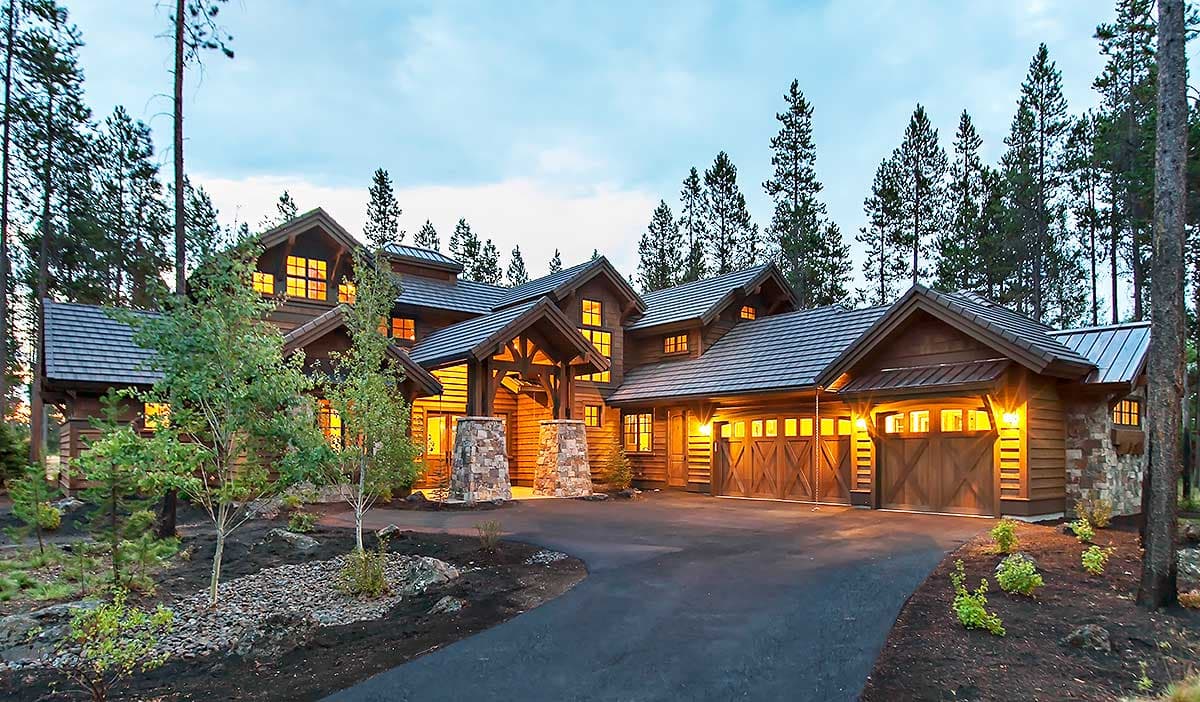 Log home exterior with multiple gables, stone accents, and a three-car garage with wood doors.
