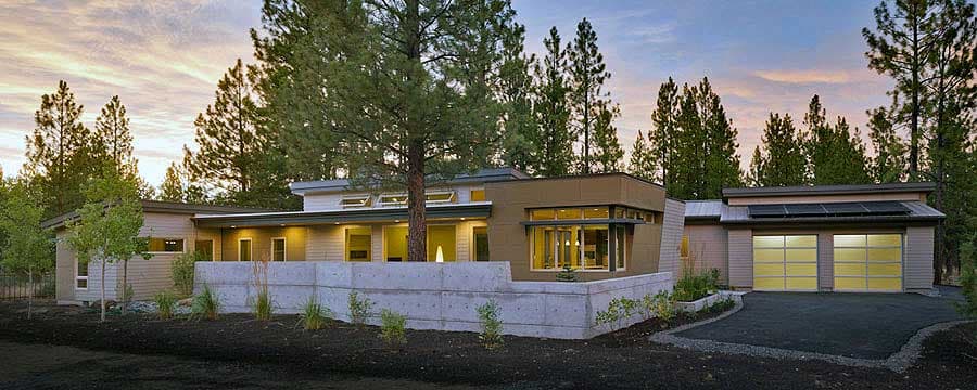 Modern ranch house plan exterior with flat rooflines, clerestory windows, concrete retaining wall, and a two-car garage with glass doors.