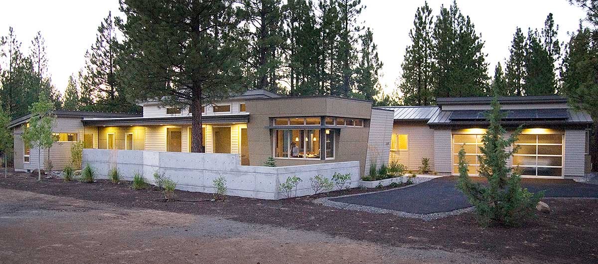 Modern house plan exterior with horizontal siding, large windows, flat roof, concrete retaining wall, and glass garage doors.