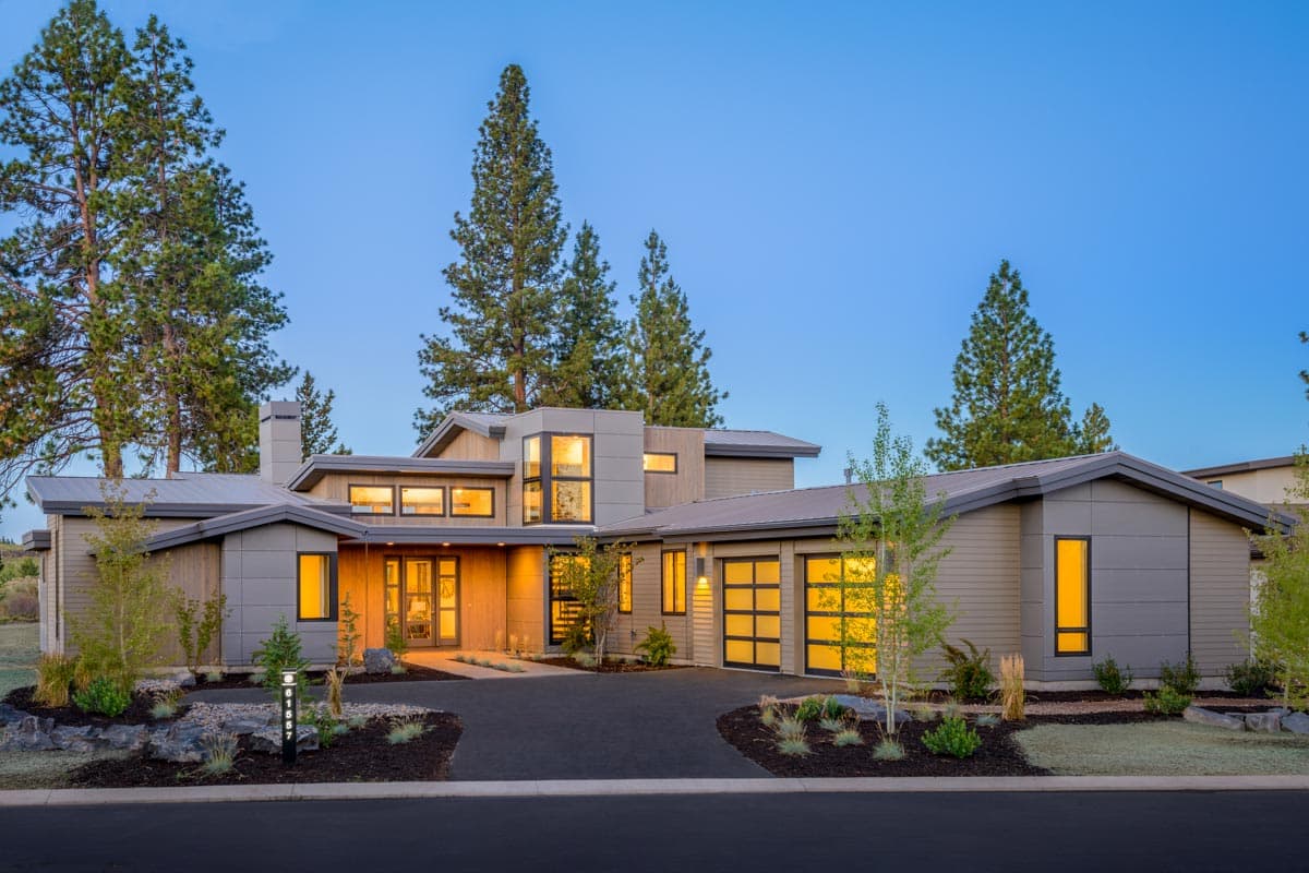 Modern house plan exterior with a low-slung profile, metal roof, wood siding, and glass garage doors.