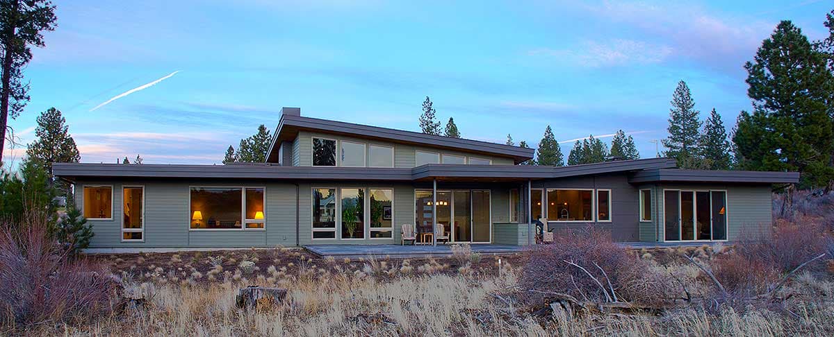 Modern house plan exterior with low-pitched roof, horizontal siding, and extensive glazing.