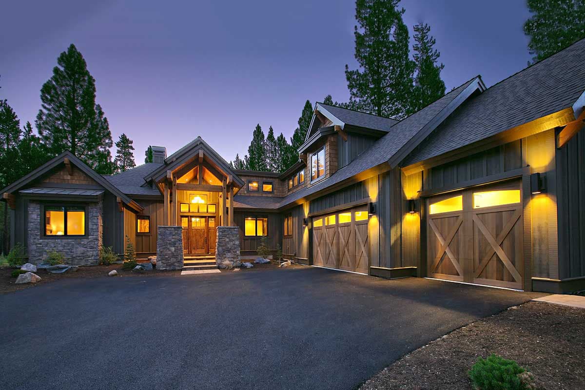 House plan exterior with stone accents, prominent gabled entry, and multiple garage doors with wood detailing.