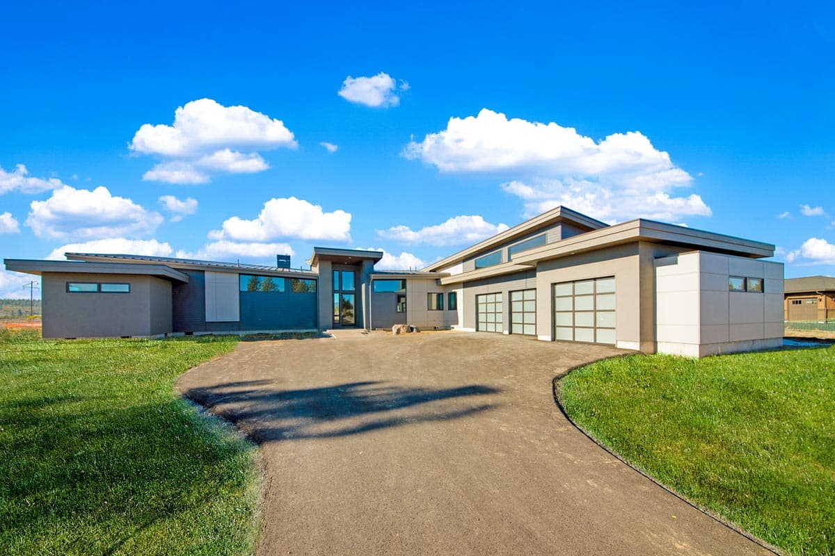 Modern house plan exterior with low-pitched roof, extensive glazing, and a three-car garage.