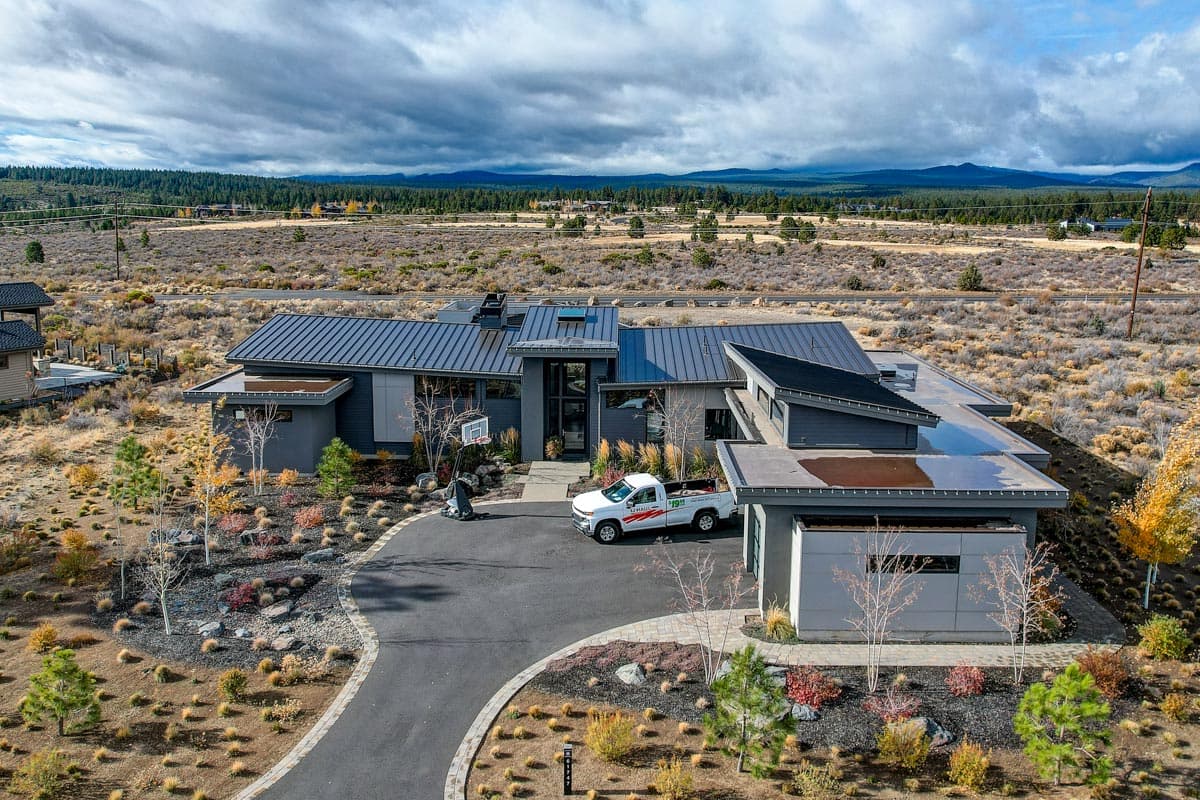 Modern house plan exterior featuring multi-level rooflines, dark metal roofing, large windows, and attached garage.