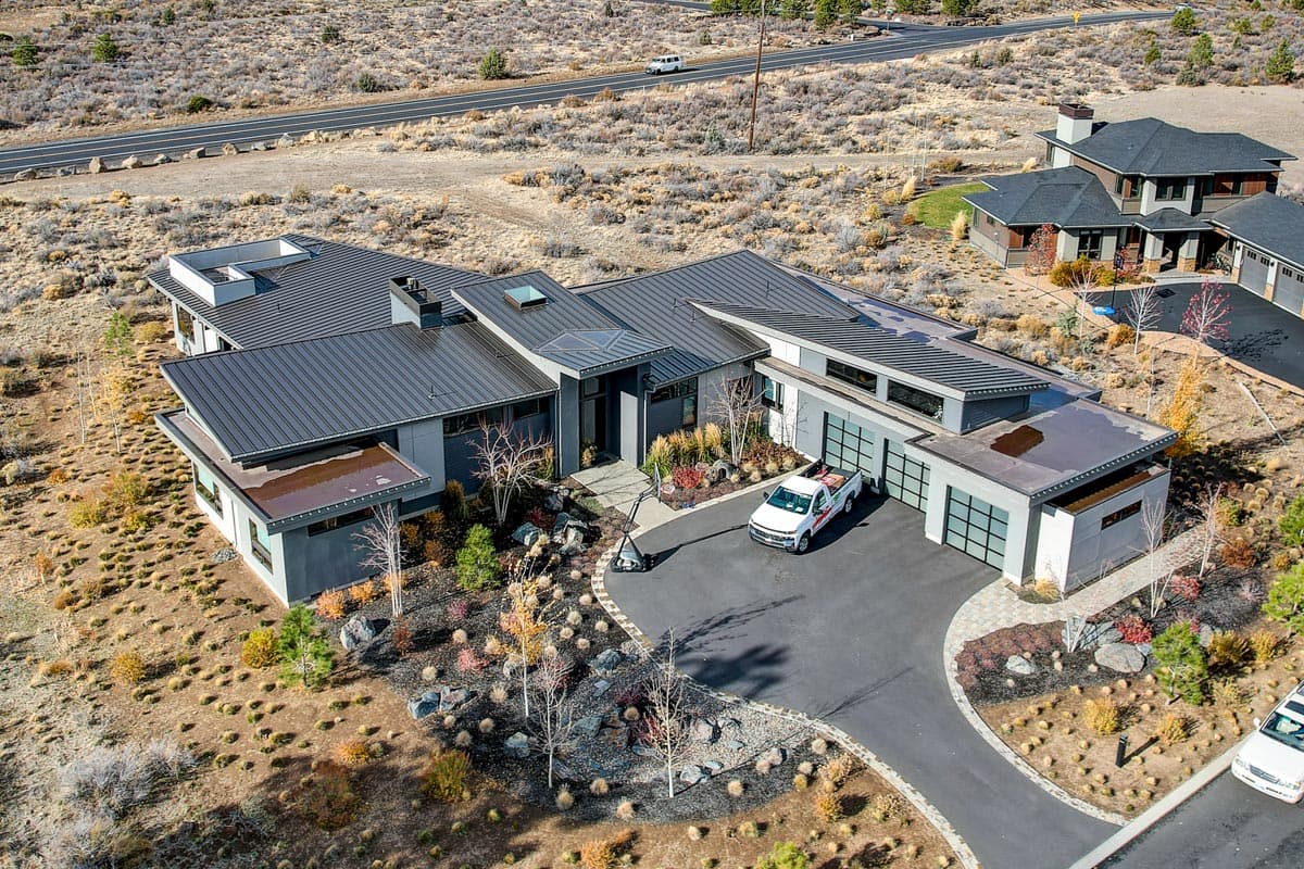 Modern house plan exterior with multiple gables, flat roof sections, and attached three-car garage.