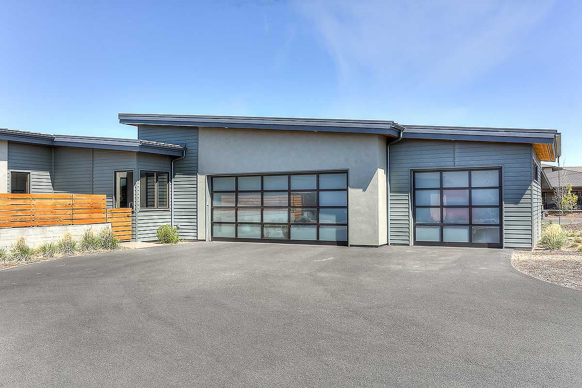 Modern house plan exterior with two glass garage doors, horizontal siding, and a flat roof.