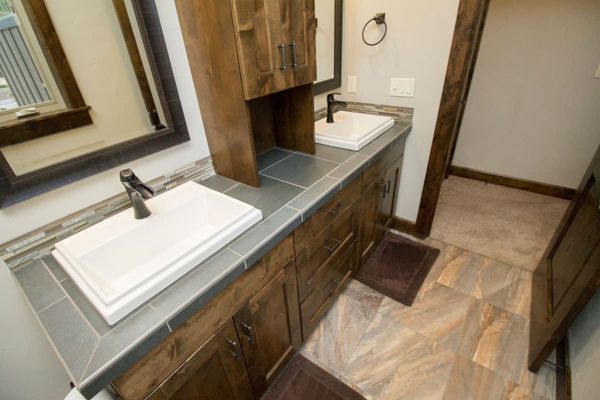 Bathroom vanity with double rectangular sinks, dark wood cabinetry, and tile floor.