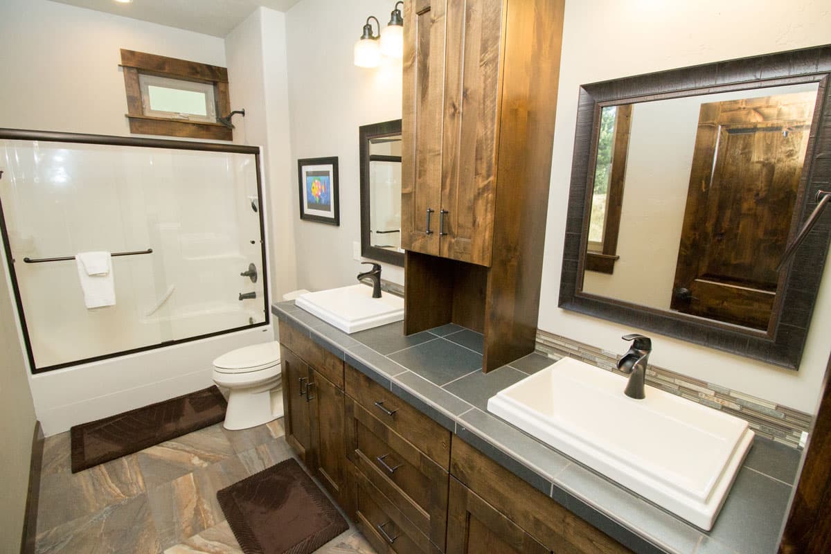 Bathroom with double vanity, white soaking tub and shower, toilet, and wood cabinetry.