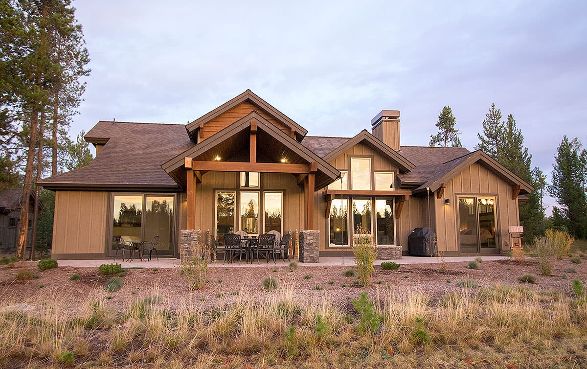 House plan exterior with multi-level roof, gables, exposed beams, stone accents, and large windows.