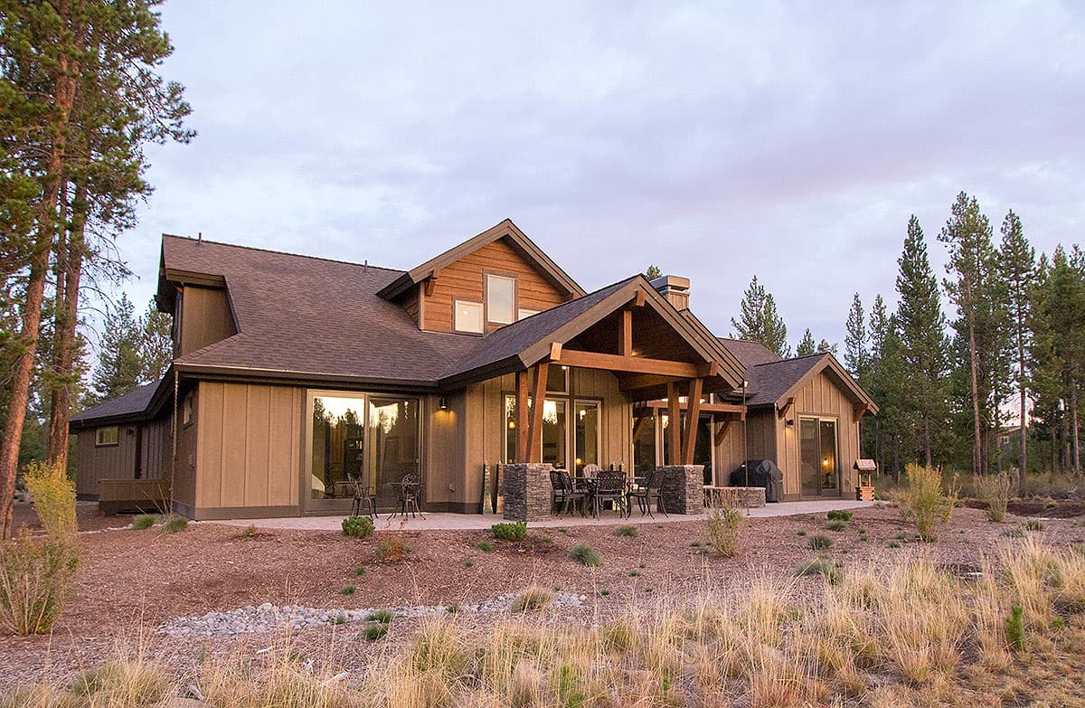 Modern house plan exterior with gabled roof, exposed beams, stone-clad porch supports, and large windows.