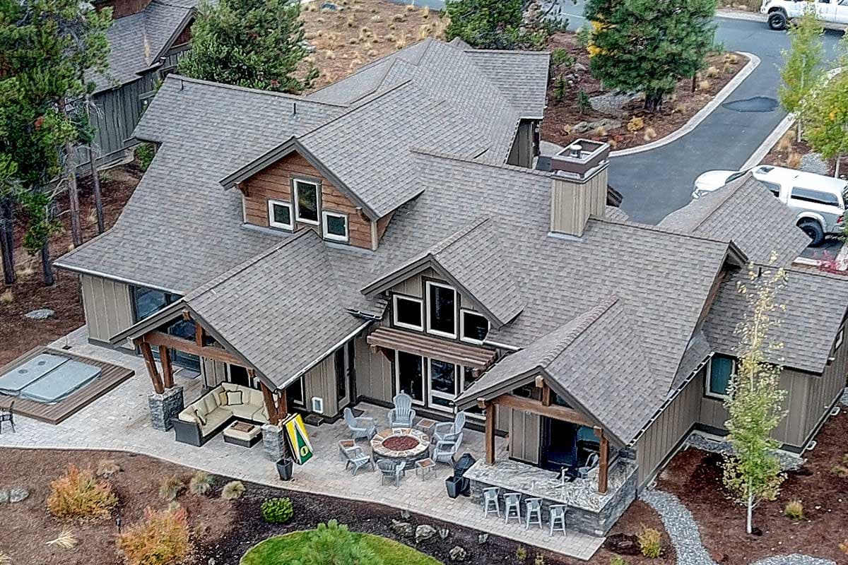 House plan exterior with gabled dormers, covered porches with stone accents, and multiple rooflines.