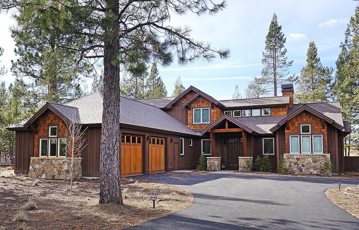 House plan exterior: Modern lodge style with two-car garage, stone and wood siding, and prominent gables.