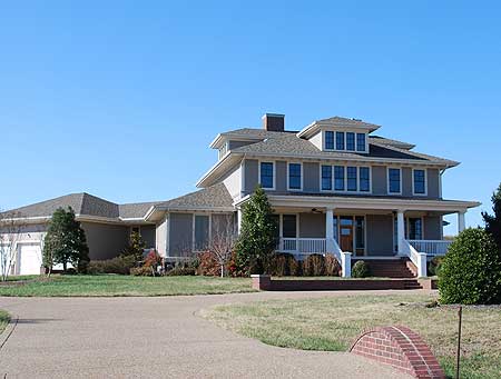 House plan exterior of a two-story home with a wraparound porch, multiple gables, and attached garage.