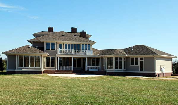 House plan exterior, two-story structure with hip roof, multi-pane windows, covered porch with white railings, and projecting gabled sections.
