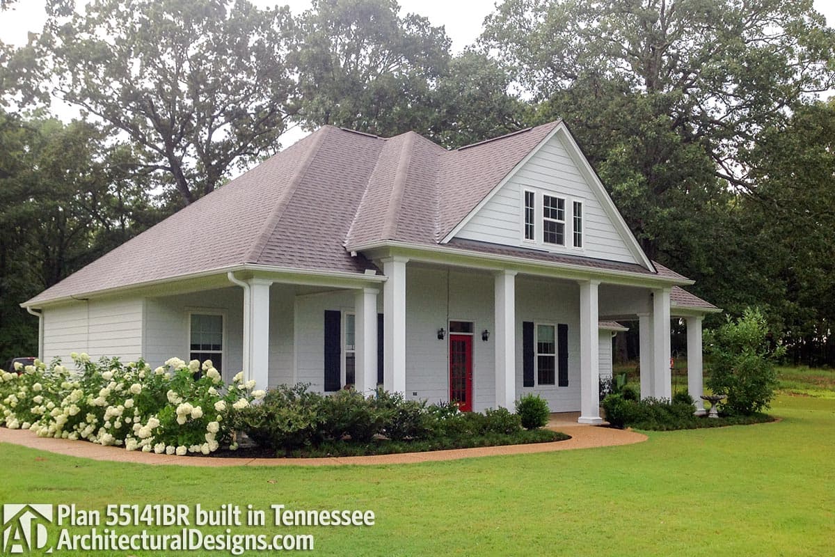 House plan exterior: Single-story home with wrap-around porch, gabled dormer, and white siding.