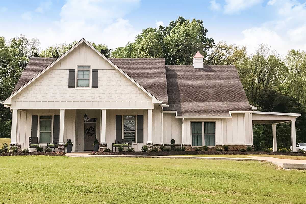 House plan exterior: A two-story Modern Farmhouse with a gabled front, covered porch supported by columns, and a detached carport.