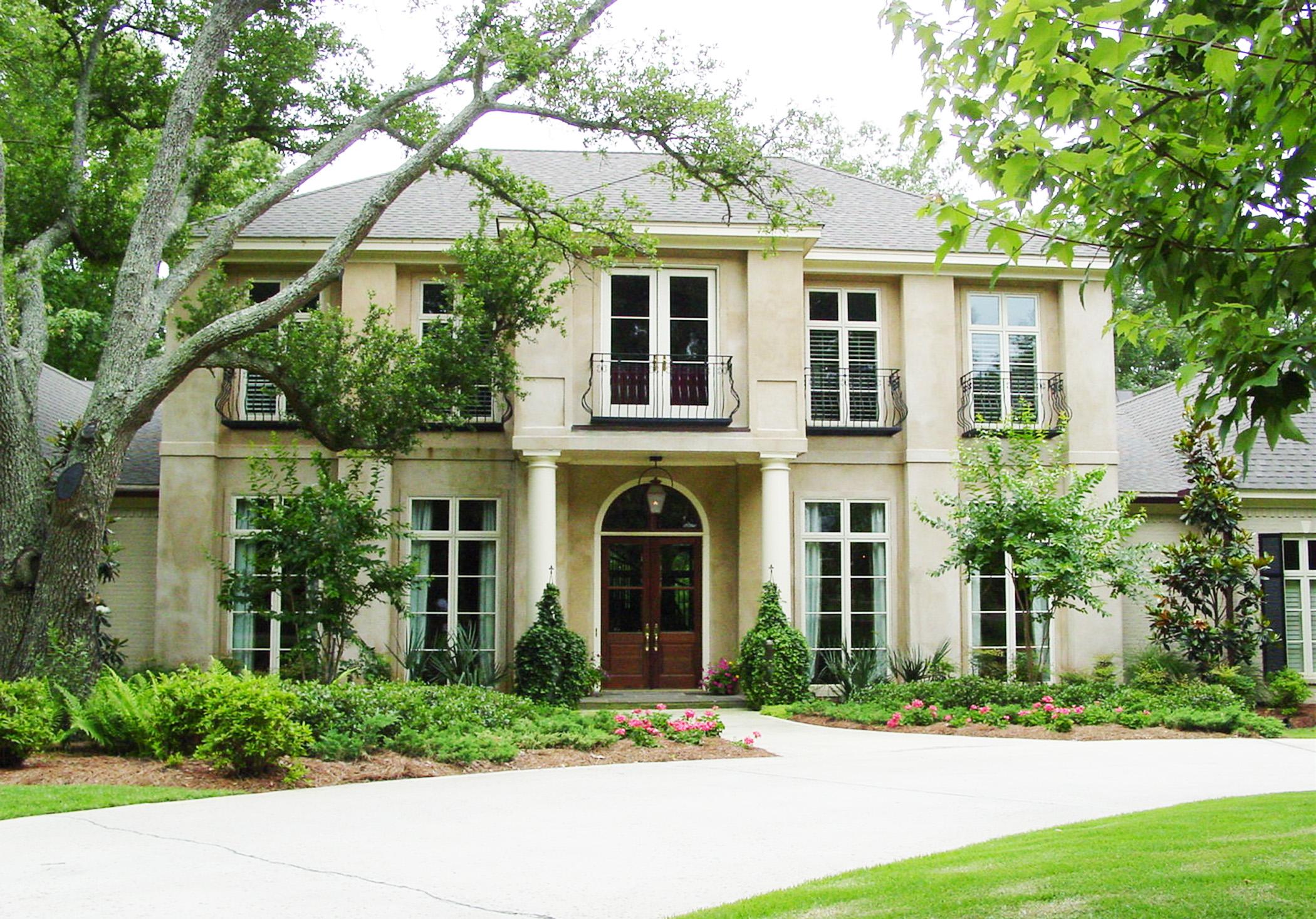 House plan exterior: Two-story stucco home with arched entryway, dormer windows, and Juliette balconies.