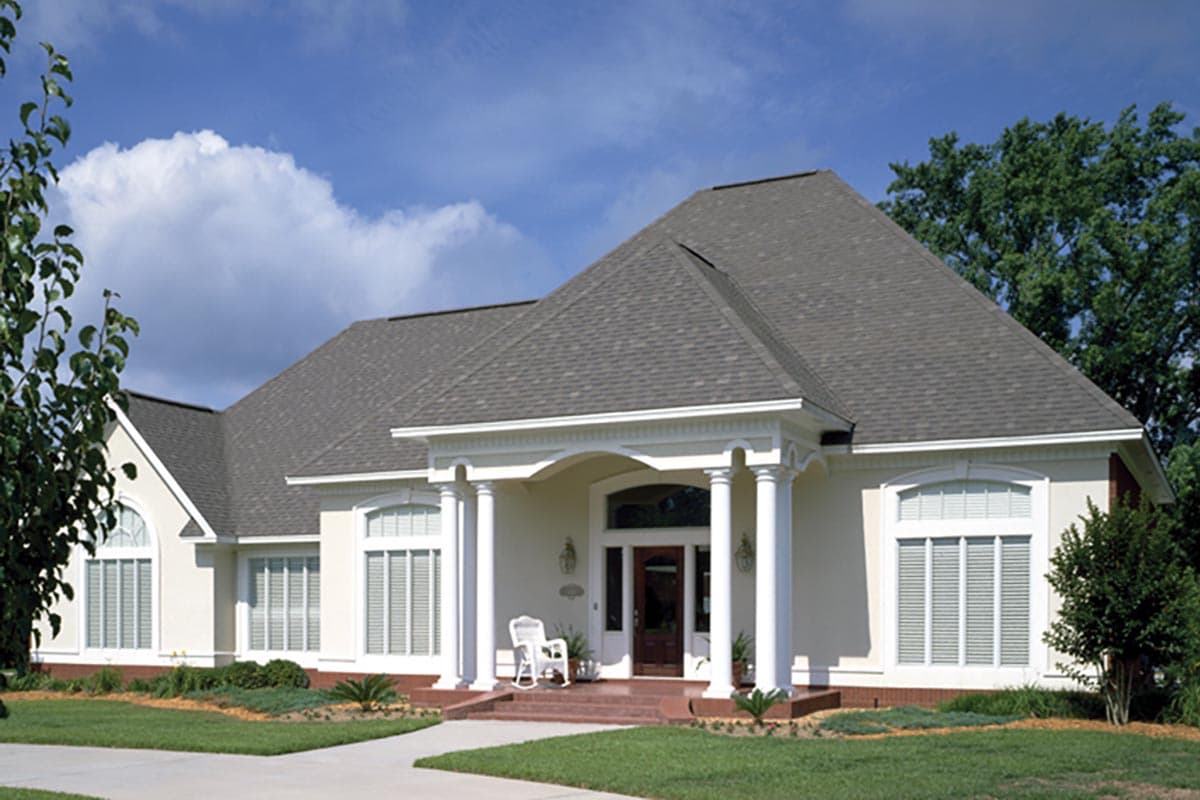 House plan exterior with a hipped roof, arched windows, and a covered portico supported by columns.