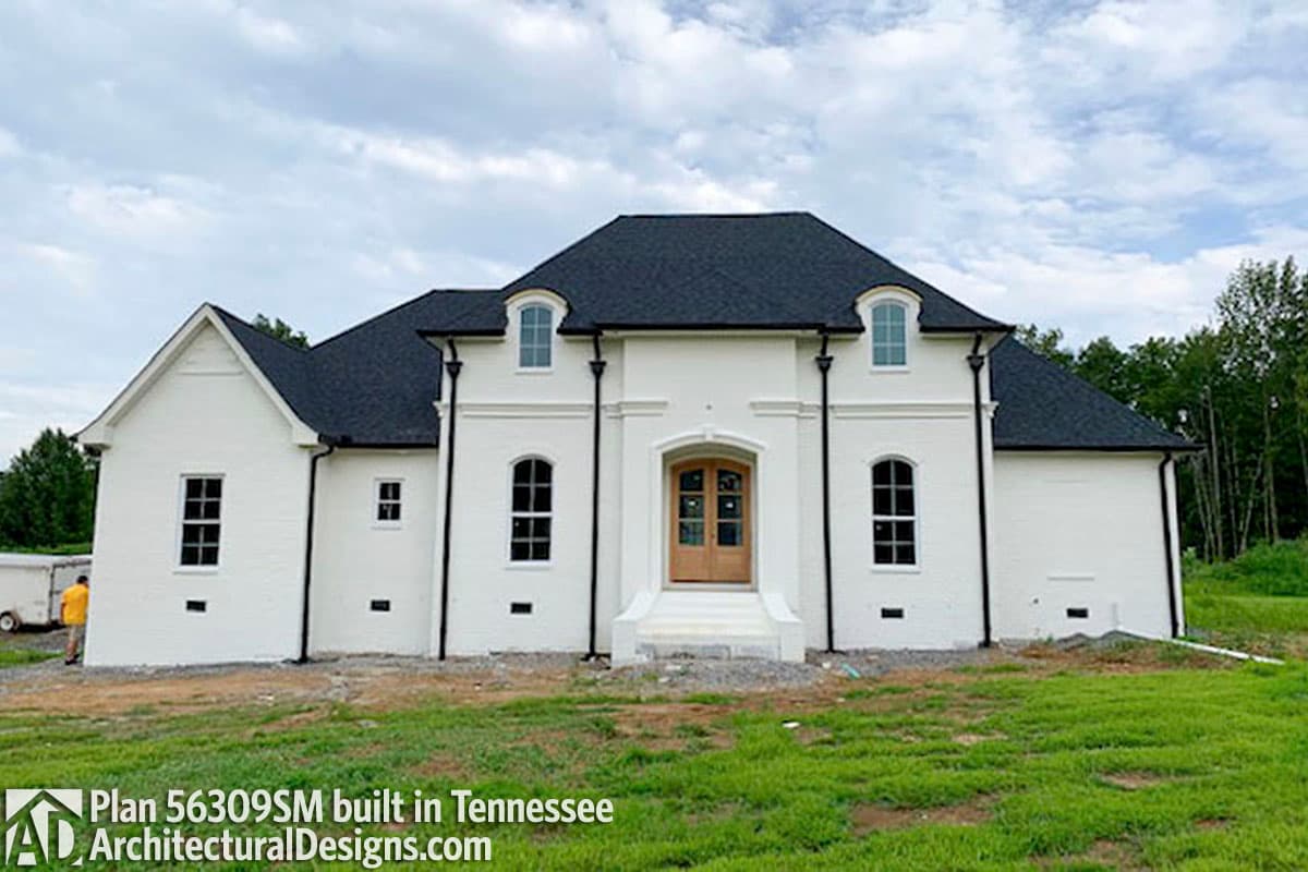 House plan exterior: Two-story Modern European style home with white brick, arched windows, prominent entrance, and dark roof.