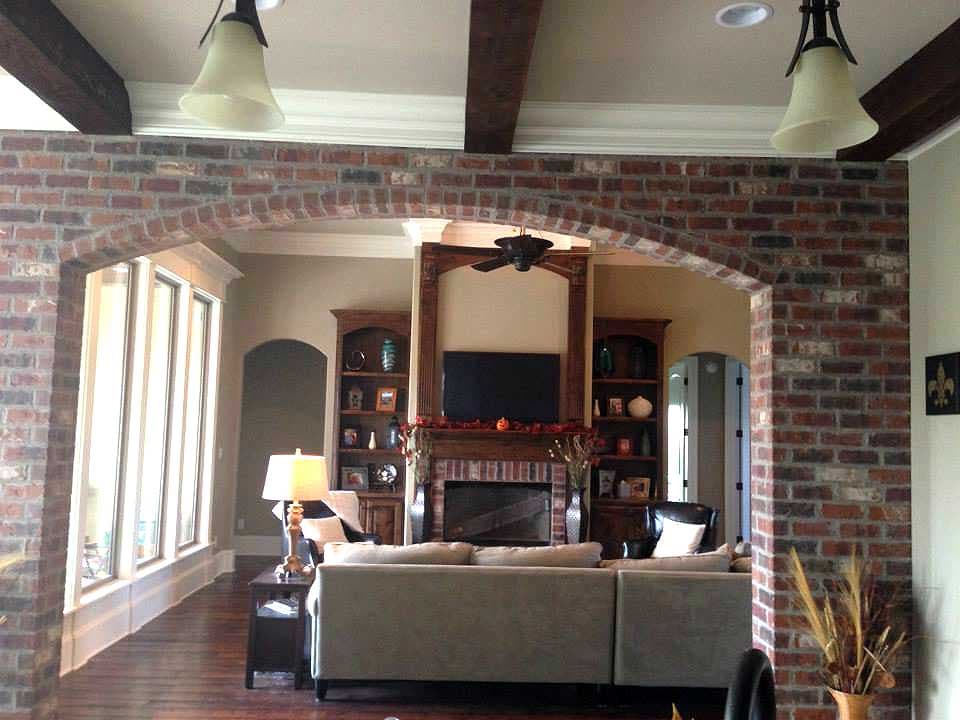 Living room interior featuring brick archway, fireplace with built-in shelving, and large windows.
