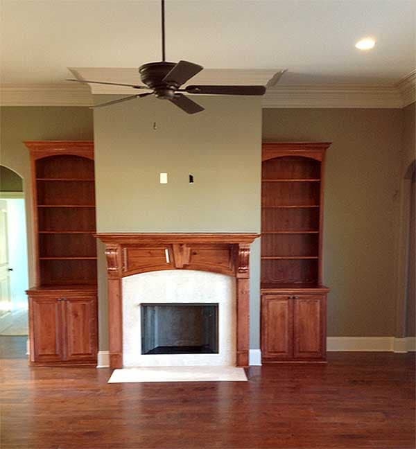 Living room with fireplace, built-in bookshelves, and ceiling fan.