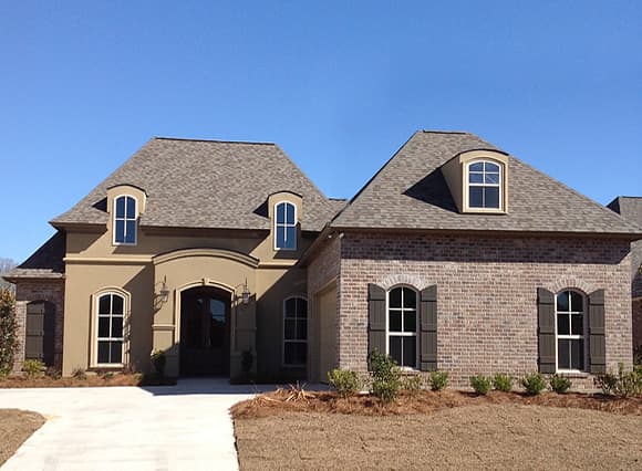 House plan exterior with brick and stucco facade, arched entryway, dormers, and multi-level roof.
