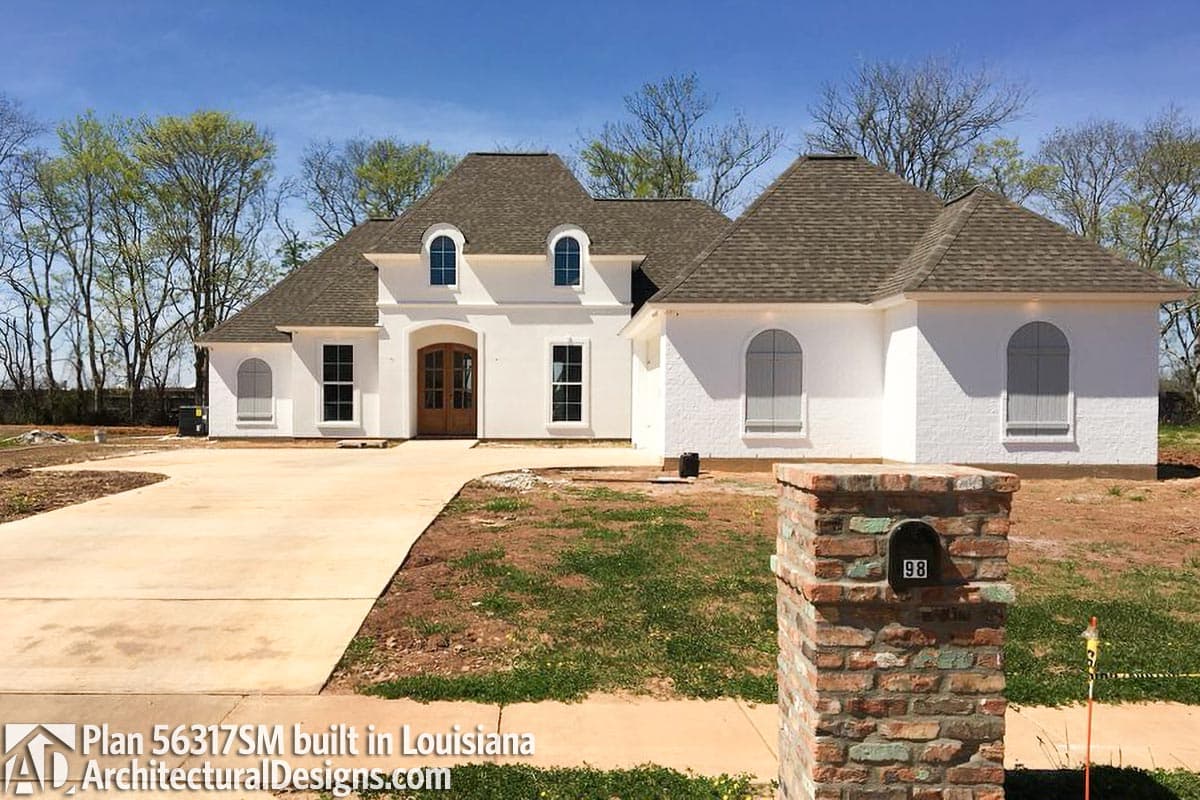 House plan exterior, two-story Modern French house with arched dormers, double entry doors, and stucco finish.
