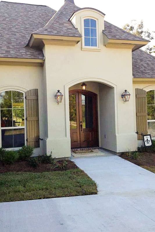 French Provincial house plan exterior with arched entry, double doors, shutters, and dormer window.