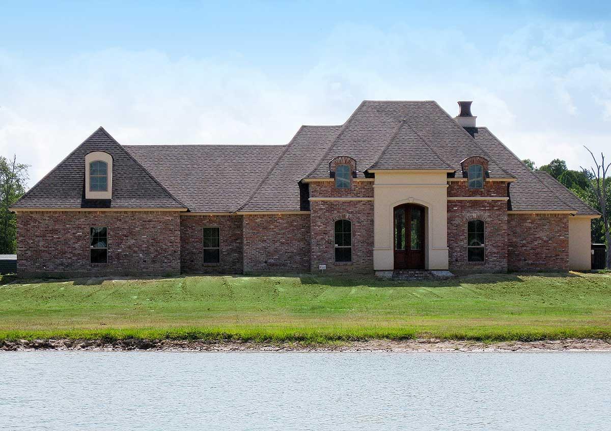 House plan exterior, brick home with arched entryway, dormer windows, and multi-level rooflines.
