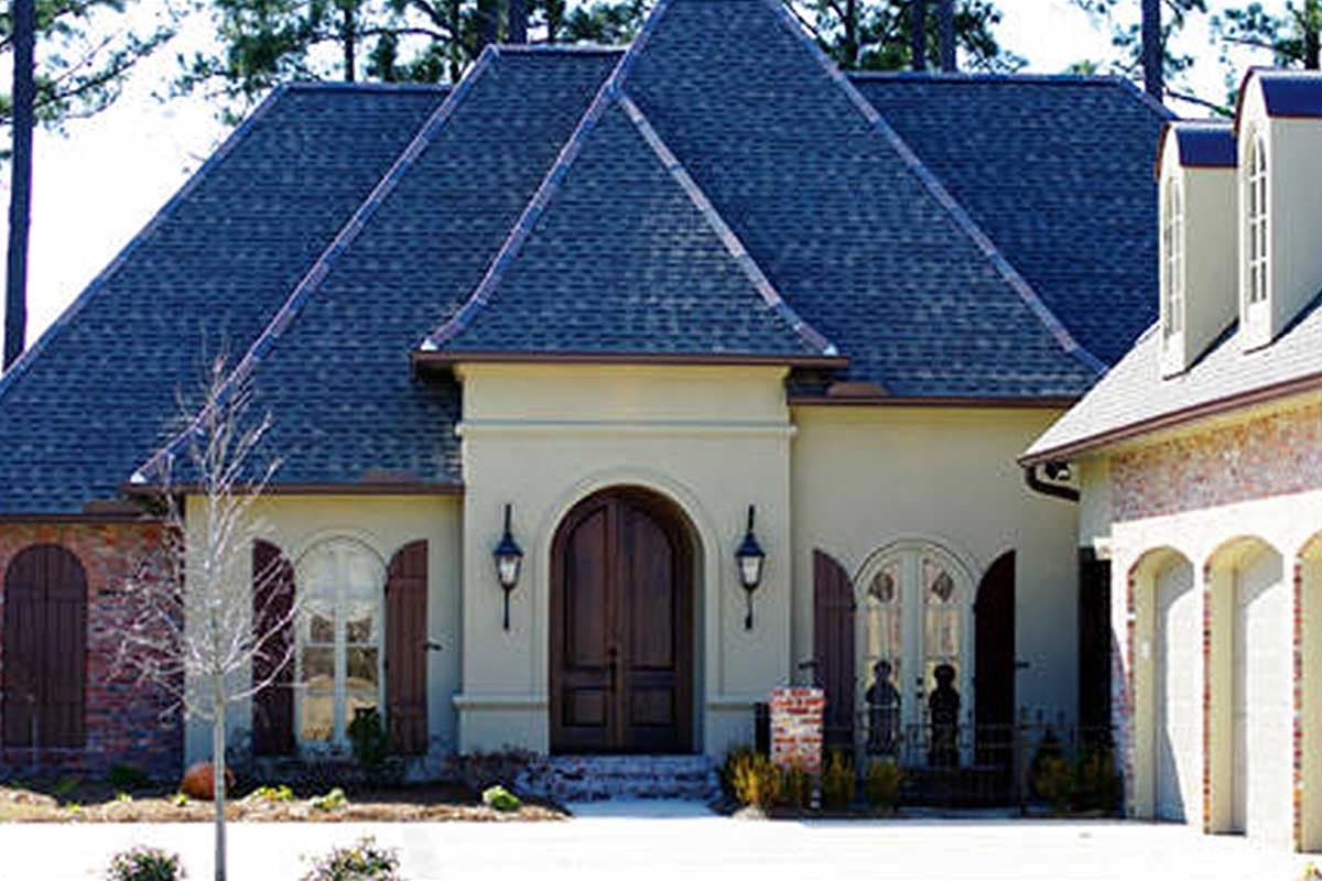 House plan exterior: French Country style with steep hipped roof, arched double doors, arched windows, and dormers.