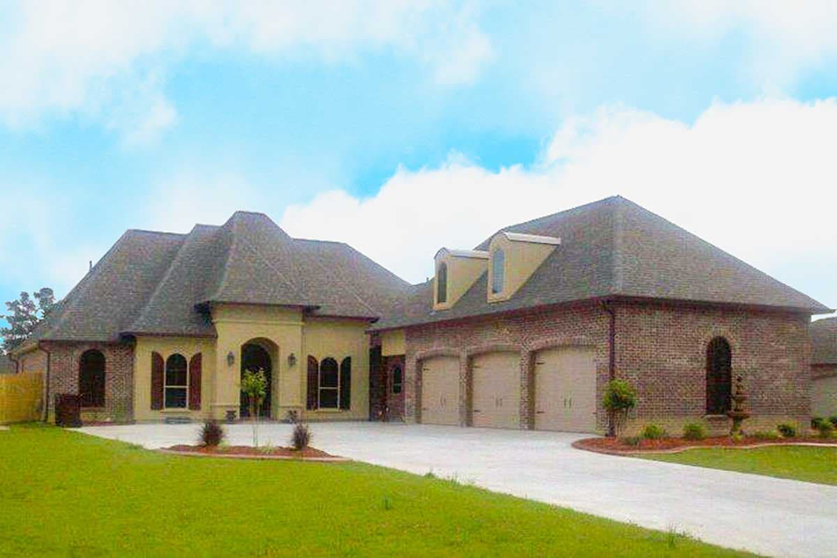 House plan exterior featuring a multi-level roof, arched entryway, and a three-car garage with dormer windows.