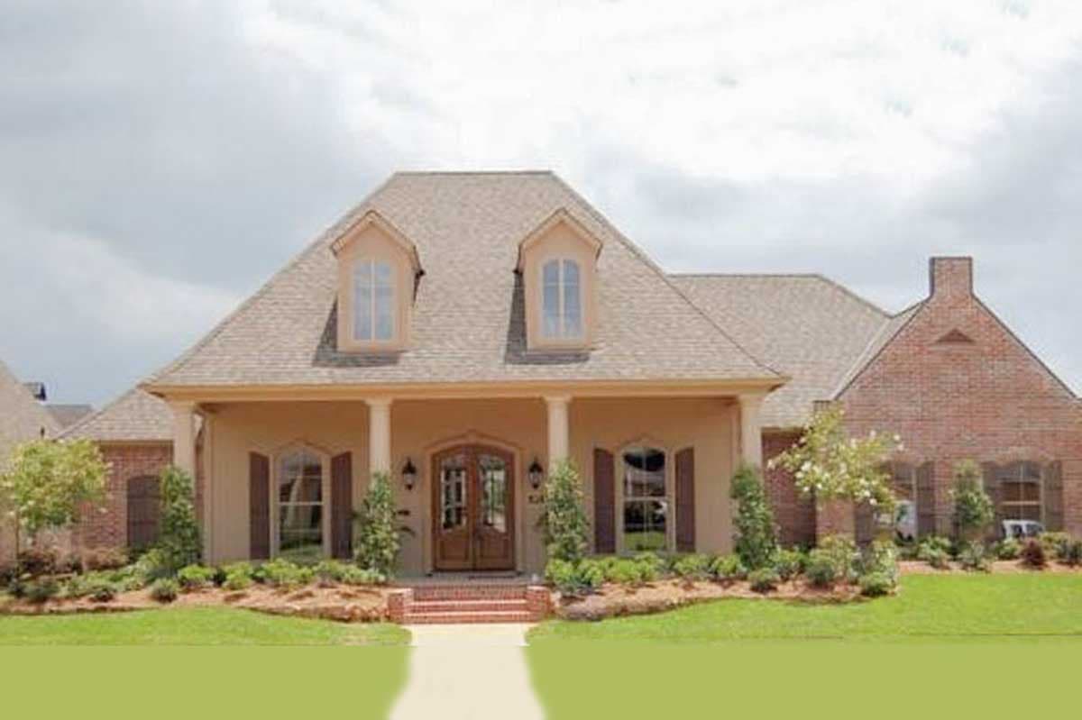 House plan exterior: One-story dwelling with covered front porch supported by columns, dormer windows, and brick accents.