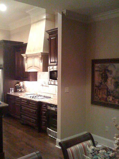 Kitchen with dark wood cabinets, granite countertops, stainless steel microwave, and gas range. Features ornate range hood.