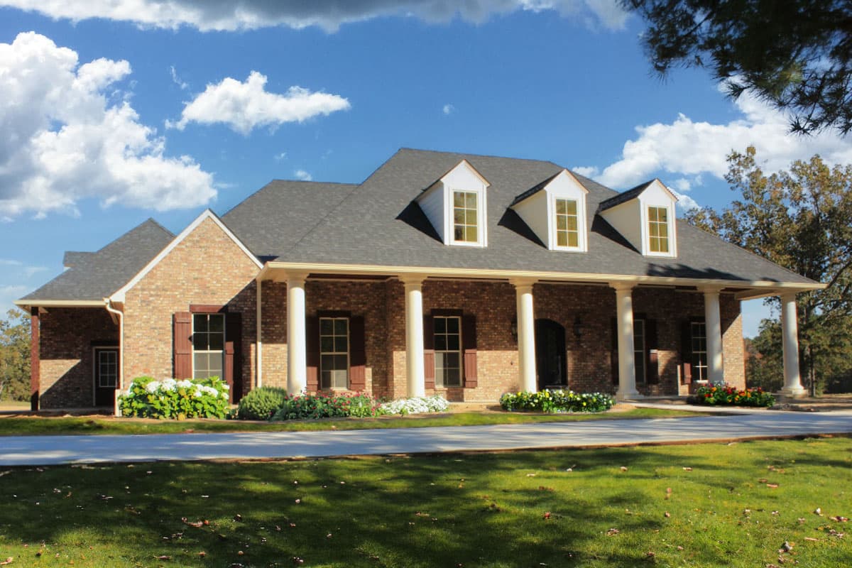 House plan exterior with brick facade, covered porch supported by columns, and dormer windows.