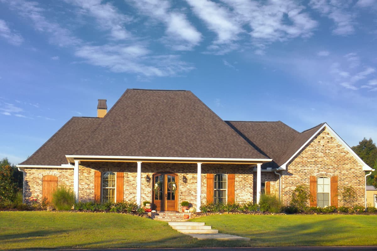House plan exterior: Brick ranch with hip roof, covered front porch supported by white columns, double entry doors, and arched windows.