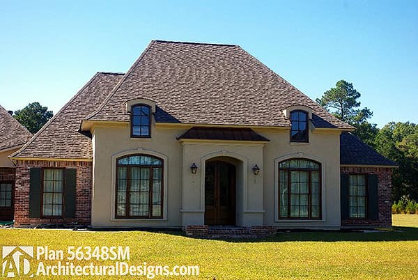 House plan exterior: French Provincial style, two stories, arched dormers, prominent arched entryway with copper roof, brick and stucco facade.