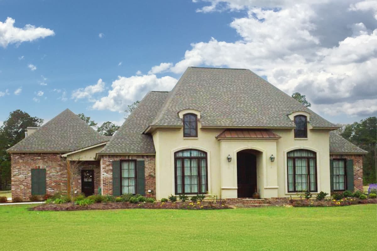 House plan exterior featuring a stucco and brick facade, arched entryway, dormer window, and multi-level roof.