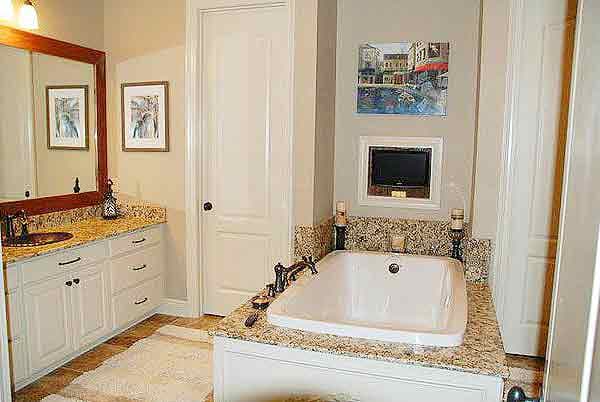 Bathroom with a soaking tub, double vanity, framed mirror, and recessed television.