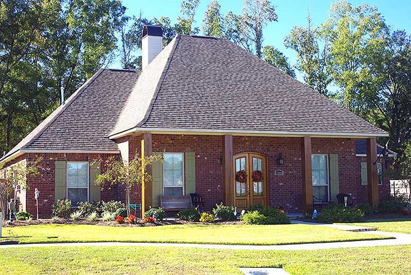 House plan exterior: One-story brick home with hip roof, covered front porch with wood columns, double entry doors, and gable dormers.