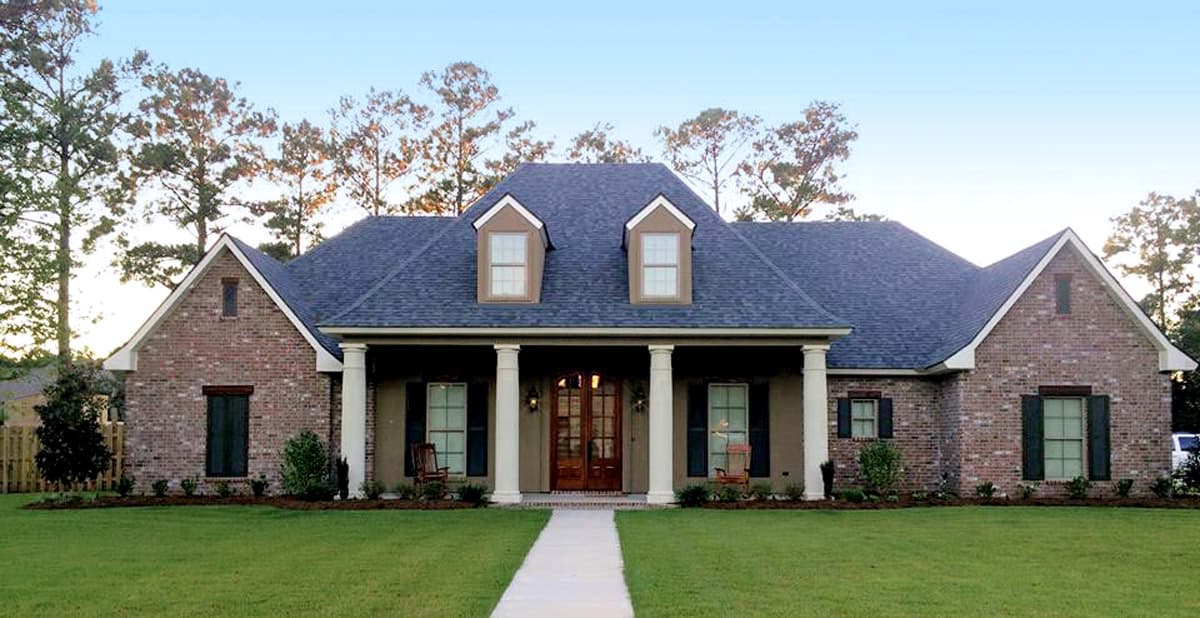 House plan exterior: Brick one-story home with a covered front porch supported by columns and two dormer windows.