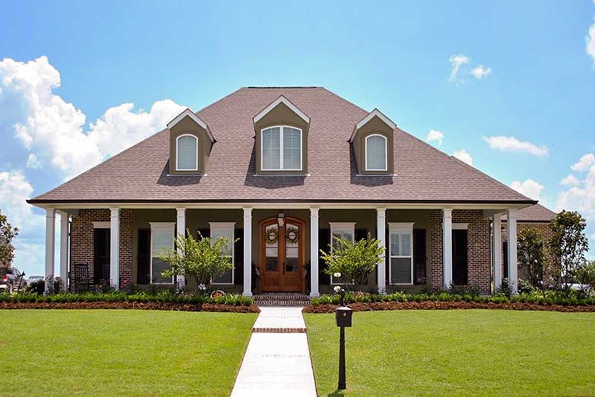 House plan exterior. Two-story home with dormers, a covered porch with columns, and a brick and siding facade. The roof has a gable design.
