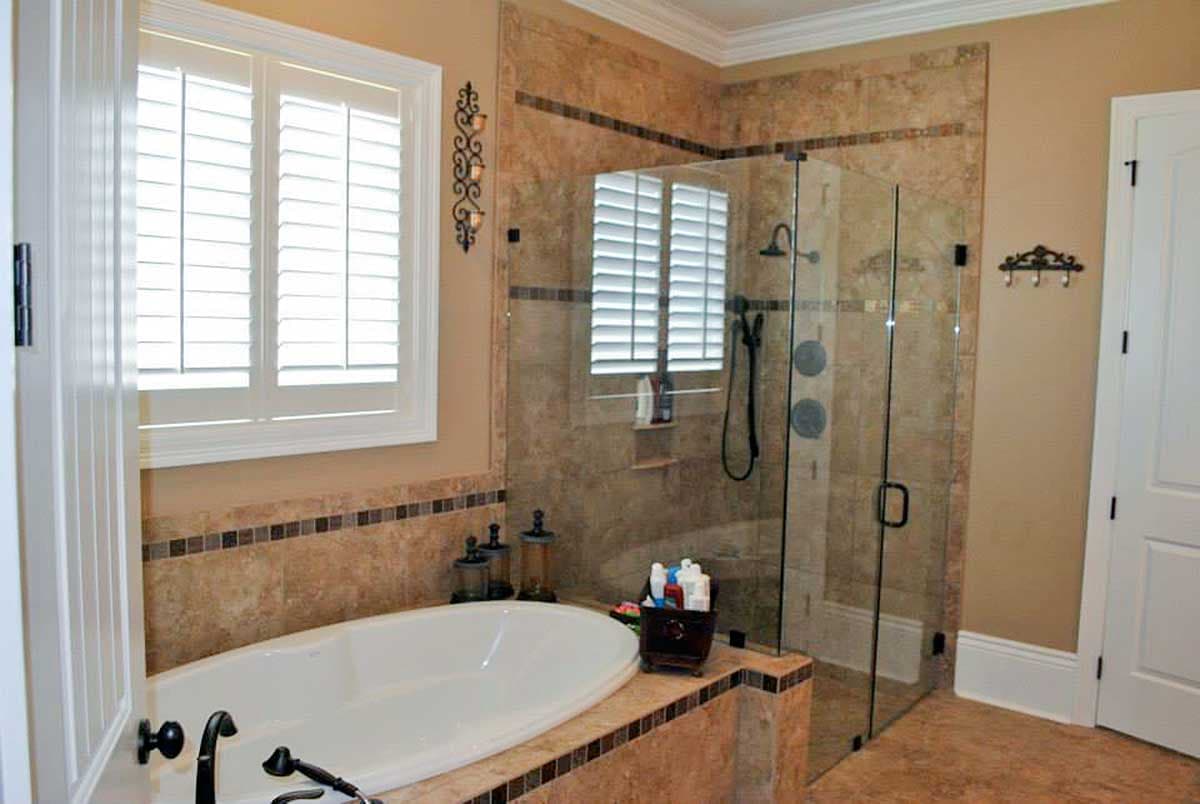 Bathroom with freestanding tub, glass-enclosed shower with tiled walls, and plantation shutters on window.