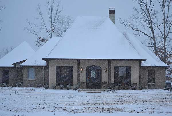 House plan exterior: One-story brick home with gabled rooflines, covered entry porch with arched opening, and multiple dormers.