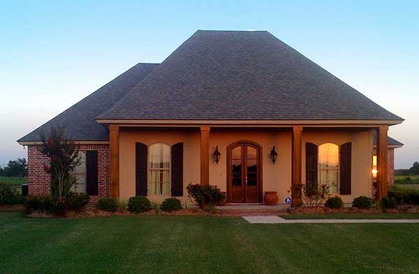 House plan exterior: one-story home with a wide covered porch, double front doors, arched windows with shutters, and brick accents.