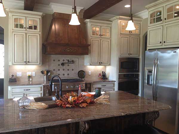 Kitchen with a large island, custom cabinetry, stainless steel appliances, and a wooden range hood.